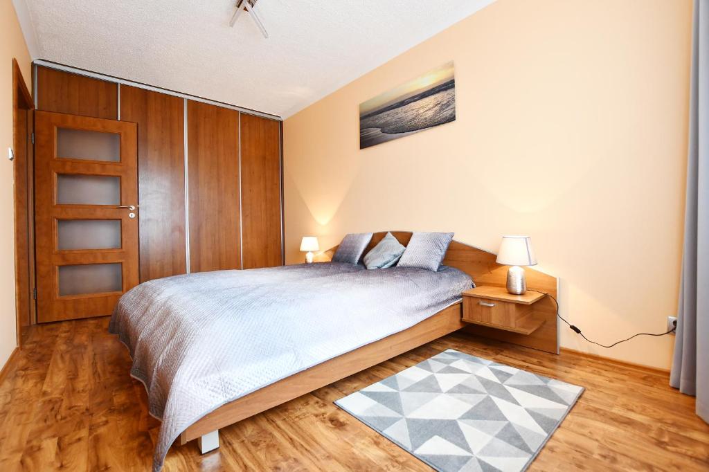 - une chambre avec un lit king-size et des placards en bois dans l'établissement MIZU Apartamenty - Zielone Tarasy, à Kołobrzeg