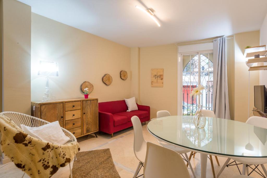 uma sala de estar com uma mesa de vidro e um sofá vermelho em GR0-Quiet apartment, Private backyard, Walk to Old Town em Málaga