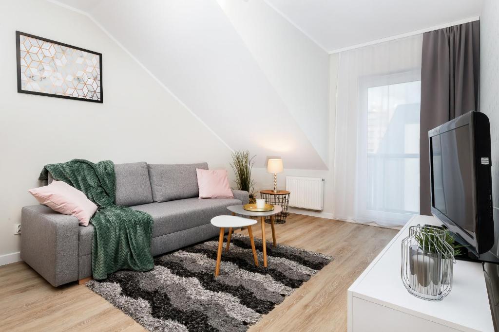 a living room with a couch and a tv at Apartments Gdańsk Kochanowskiego by Renters in Gdańsk