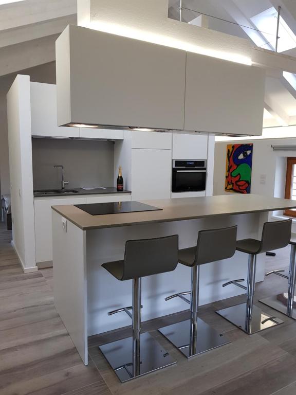 a kitchen with white cabinets and a counter with stools at Dimora diffusa Sannicolò al Fiume in Rovereto