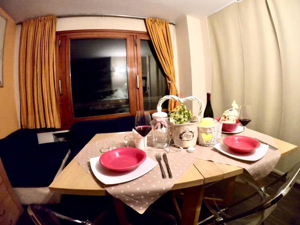 una mesa con platos rojos y copas de vino. en La finestra sulla Via Lattea en Sestriere