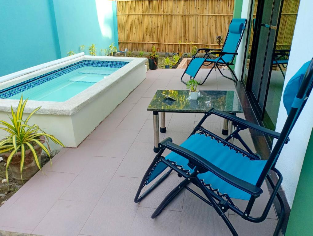 Valencia的住宿－Chez Melanie Valencia Dumaguete GetAway，庭院设有两把椅子和一张桌子,庭院内设有游泳池