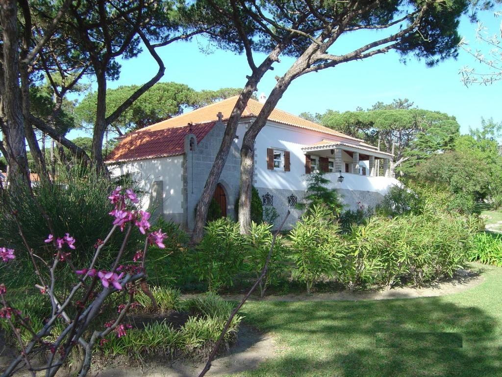 una casa blanca con techo rojo y algunas flores en Solar Do Magoito, en Sintra