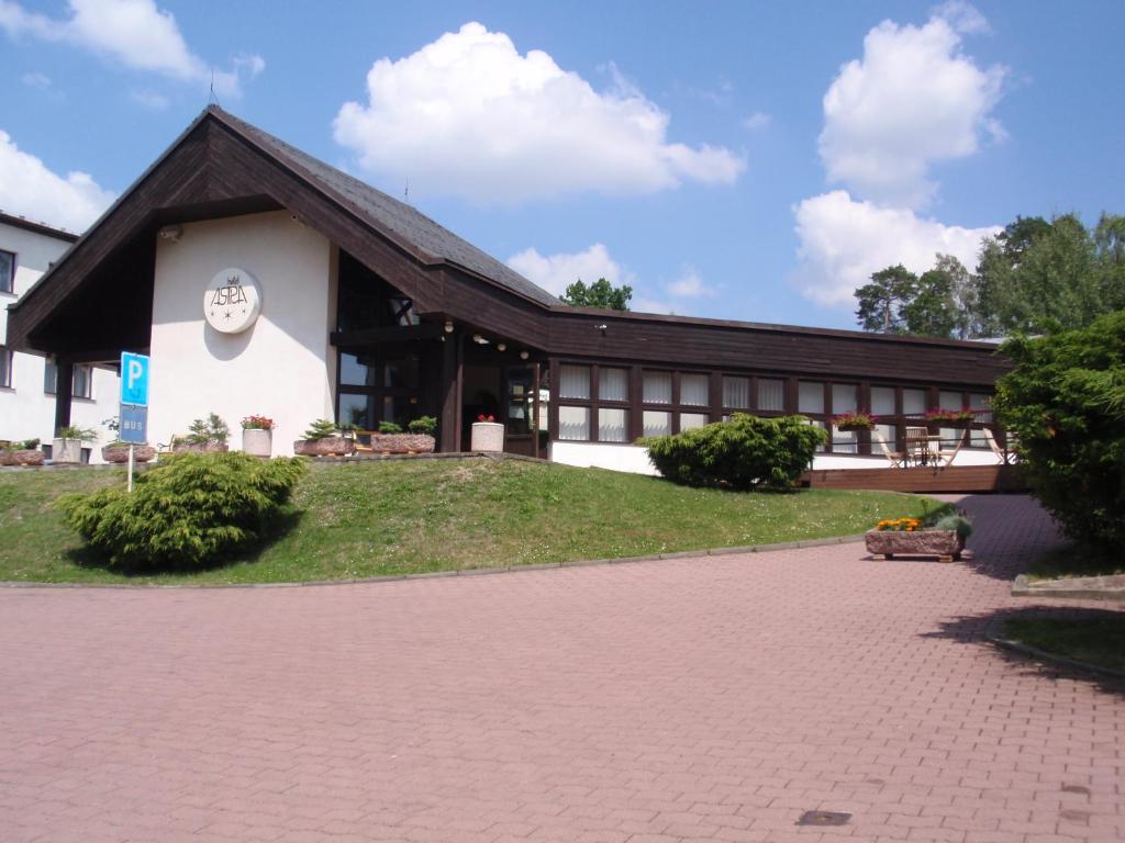 a building with a black roof and a brick driveway at Hotel Astra in Tuchlovice