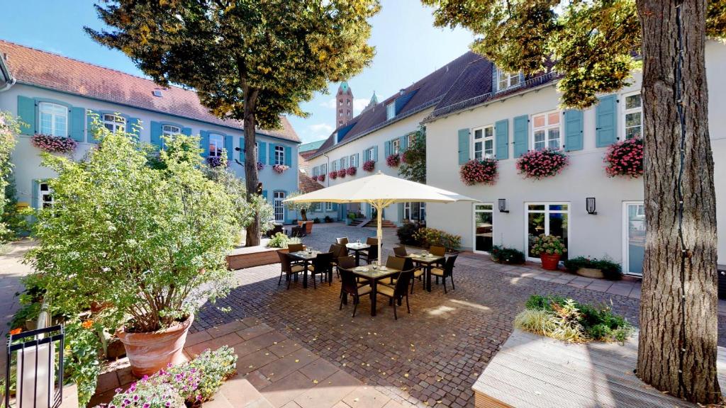 un patio al aire libre con mesas, sillas y edificios en Hotel Domhof, en Speyer