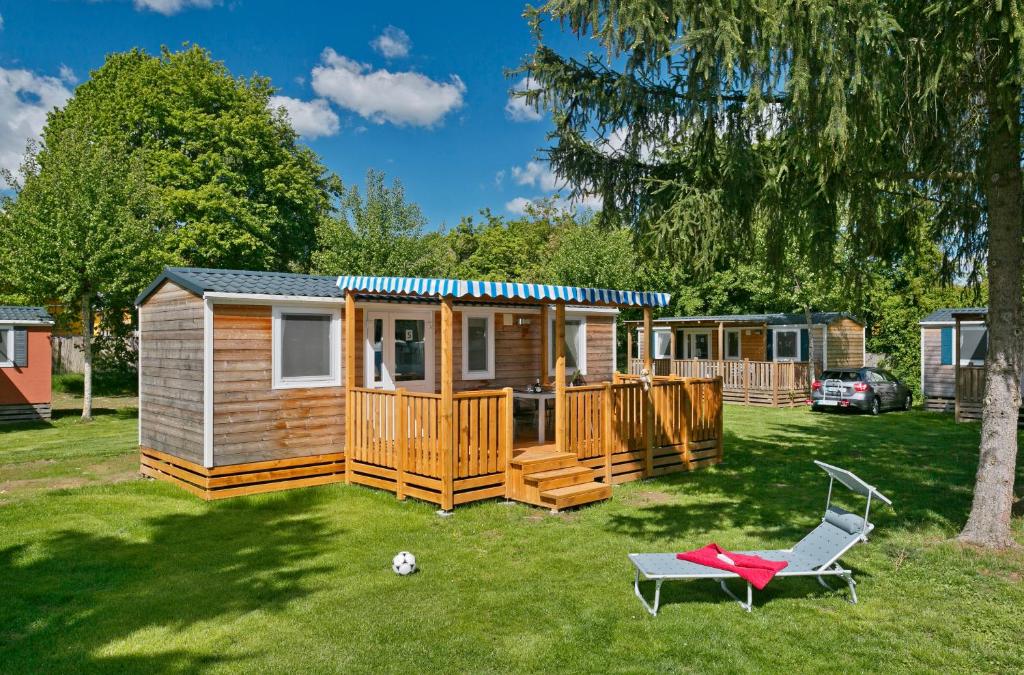 a cabin with a deck and a chair in the yard at KNAUS Campingpark Frickenhausen in Frickenhausen