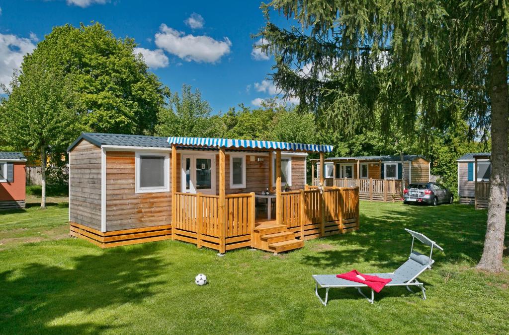 eine Hütte mit einer Terrasse und einem Stuhl im Hof in der Unterkunft KNAUS Campingpark Frickenhausen in Frickenhausen