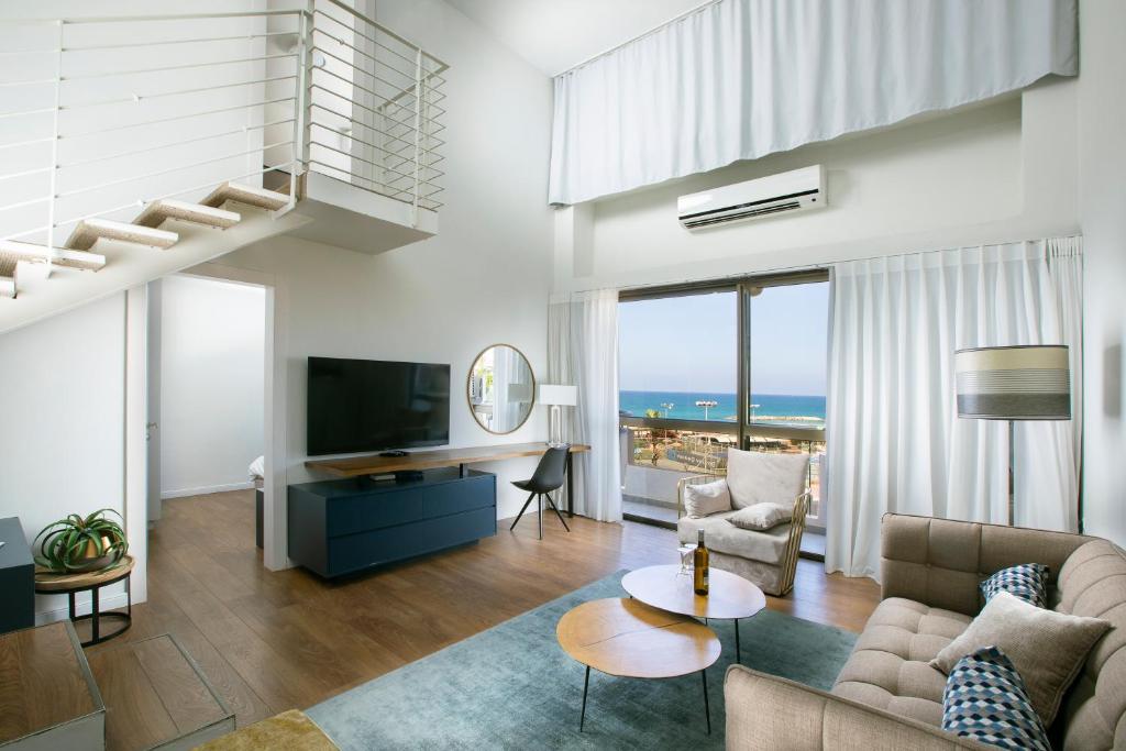 uma sala de estar com uma escada, um sofá e uma televisão em Marine Heights Suites em Herzelia 