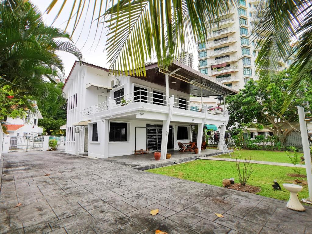 a white house with a palm tree in front of it at Little Heaven by Sky Hive, A Beach Front Bungalow in Tanjung Bungah