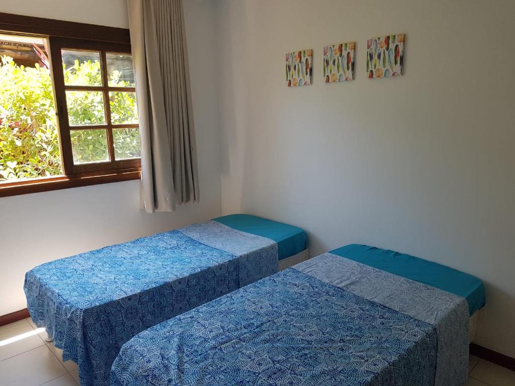 two beds in a room with a window at Porto das Baleias Praia do Forte in Praia do Forte