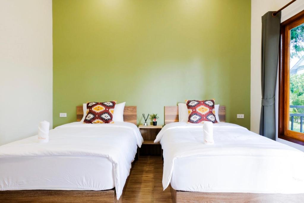 two beds in a room with green walls at The Cozy Hotel in Phetchaburi