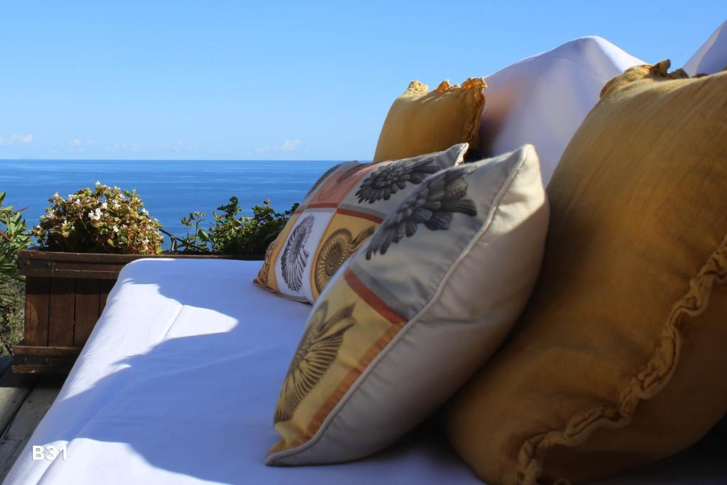 uma cama com almofadas com o oceano ao fundo em Villa Vista Mare Residence Serenamore em Favone