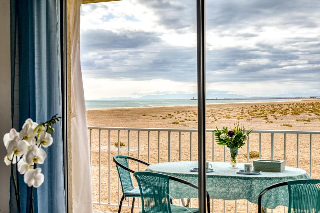 a view of the beach from a room with a table and chairs at Arcadia Appartement - Vue sur Mer in Gruissan