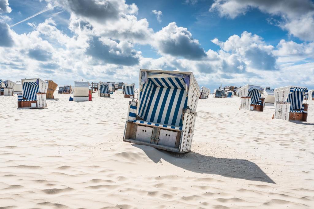 una fila di sedie a sdraio su una spiaggia sabbiosa di EBBEUNFLUT a Sankt Peter-Ording
