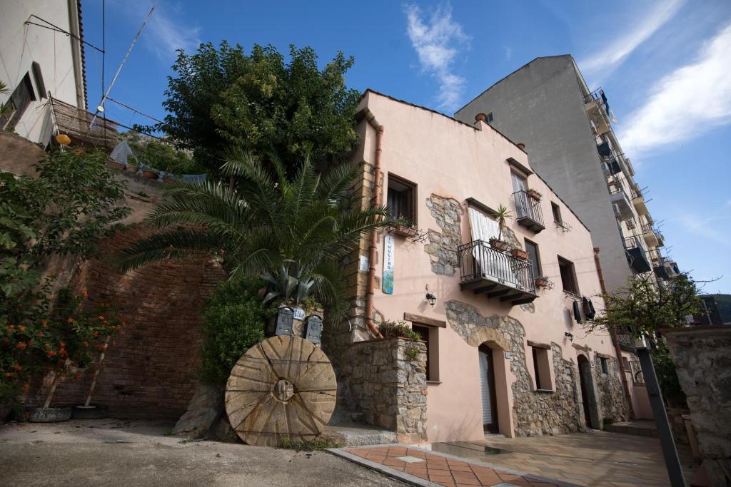 a pink building with a palm tree in front of it at Il Mulino in Cefalù