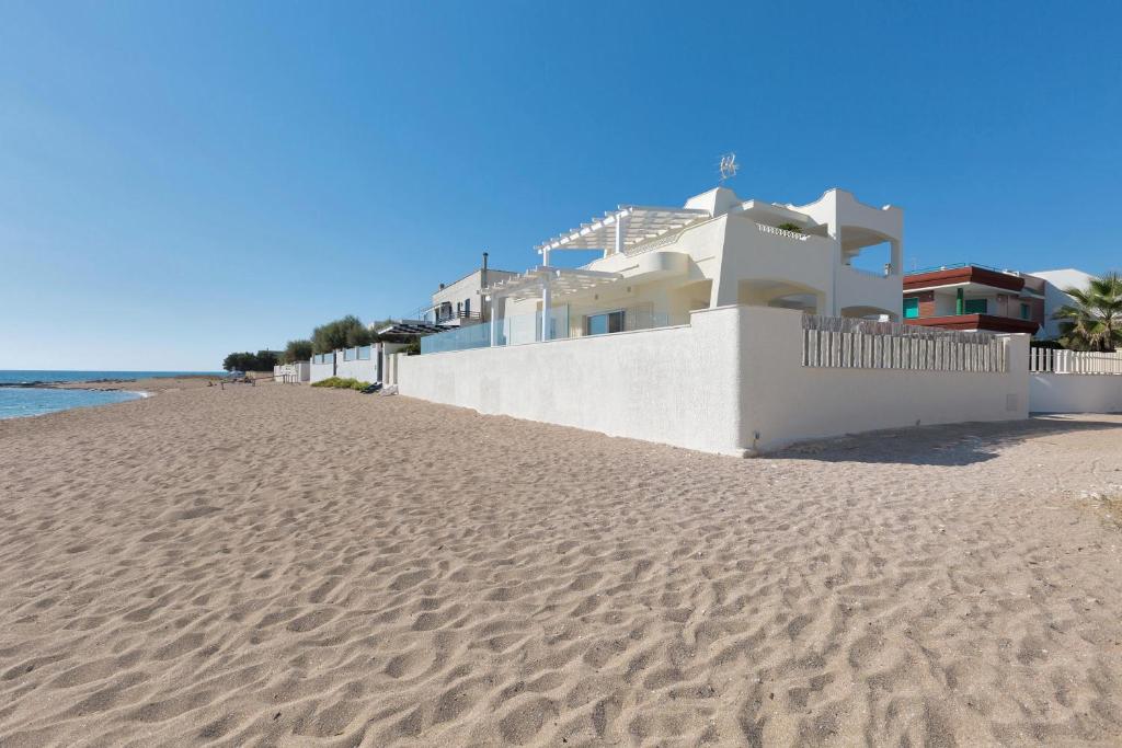 a white house on the beach next to the ocean at Villa Diamante by BarbarHouse in Maruggio