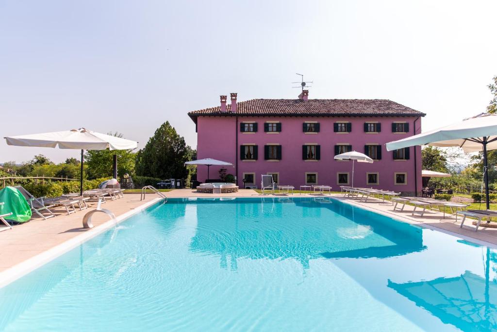 une grande piscine en face d'un bâtiment rose dans l'établissement Agriturismo Ca' Vecia, à Castelnuovo del Garda