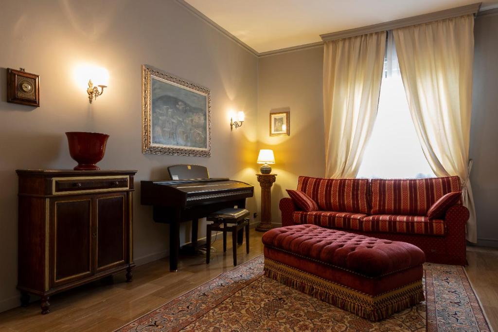 sala de estar con piano y sofá rojo en Seven Suites Pieve, en Pieve di Soligo