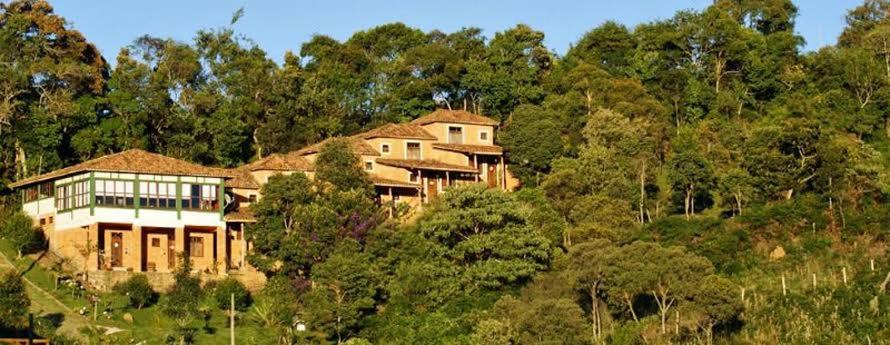 a large house on top of a hill with trees at Suítes Canela de Ema - Ibitipoca in Conceição da Ibitipoca