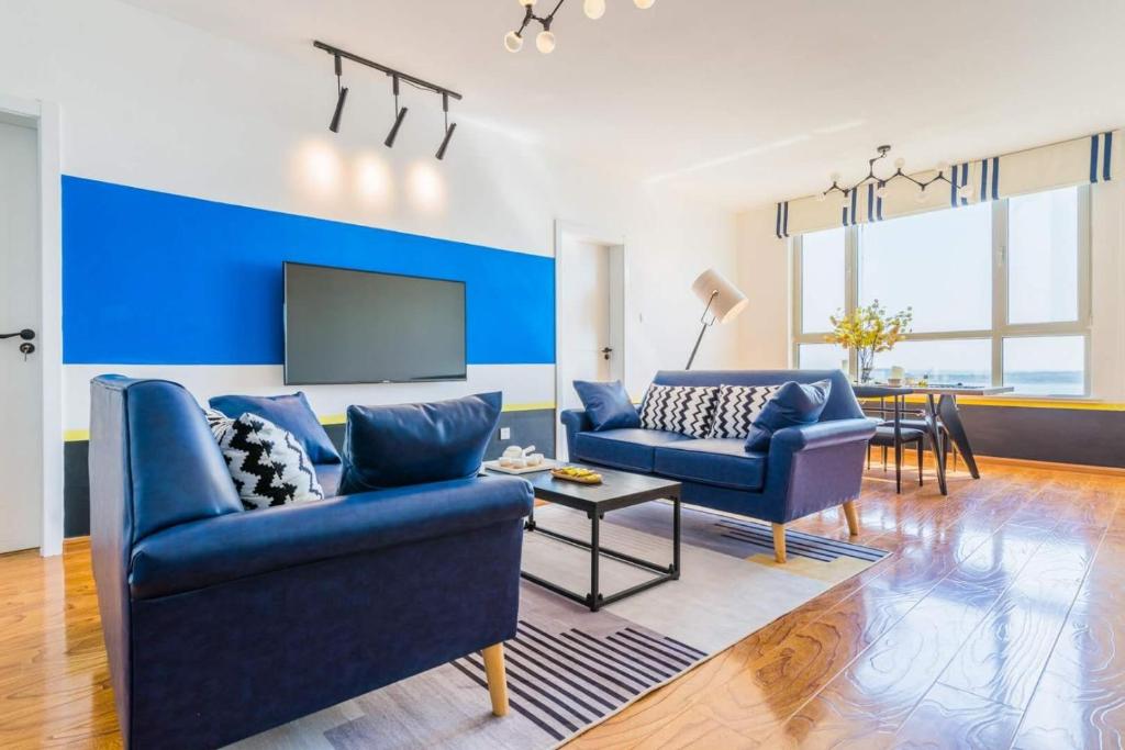 a living room with two blue couches and a tv at Qingdao Huangdao·Qingdao Silver Beach· in Qingdao