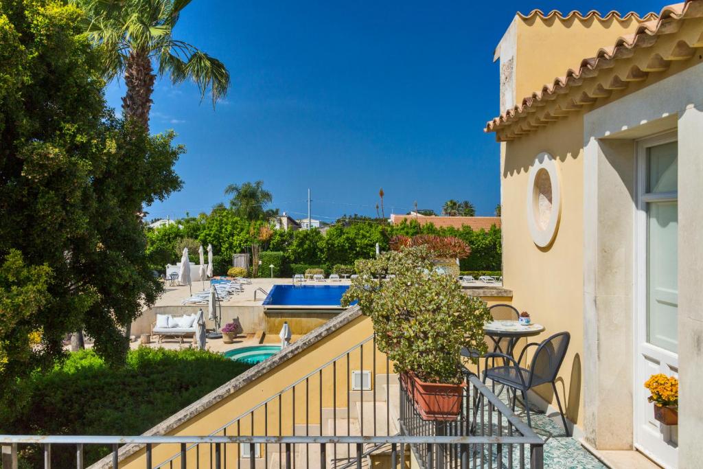 einen Balkon mit einem Tisch, Stühlen und einem Pool in der Unterkunft Caiammari Boutique Hotel & Spa in Syrakus