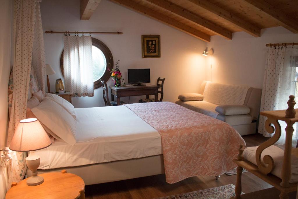 a bedroom with a bed and a chair and a desk at Al Rustico in Nago-Torbole
