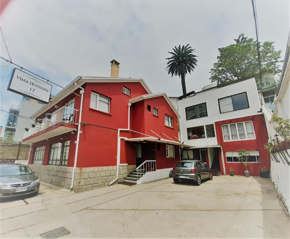 a red building with cars parked in a parking lot at Hotel Vista Hermosa 17 in Viña del Mar