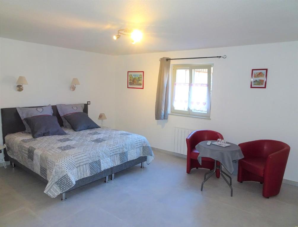 a bedroom with a bed and a table and a chair at Maison d'Hôtes Le Cep d'Or Alsace in Saint-Hippolyte