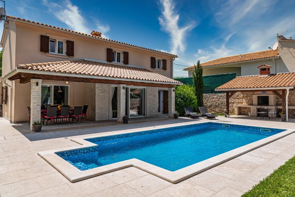 a villa with a swimming pool in front of a house at Villa Natasha - charming Istrian villa with private heated pool in Ružići