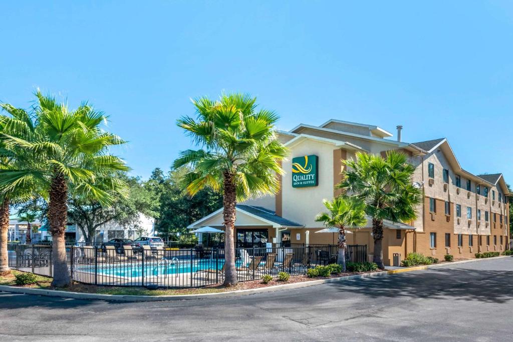 a hotel with palm trees in front of a pool at Quality Inn & Suites Leesburg Chain of Lakes in Leesburg