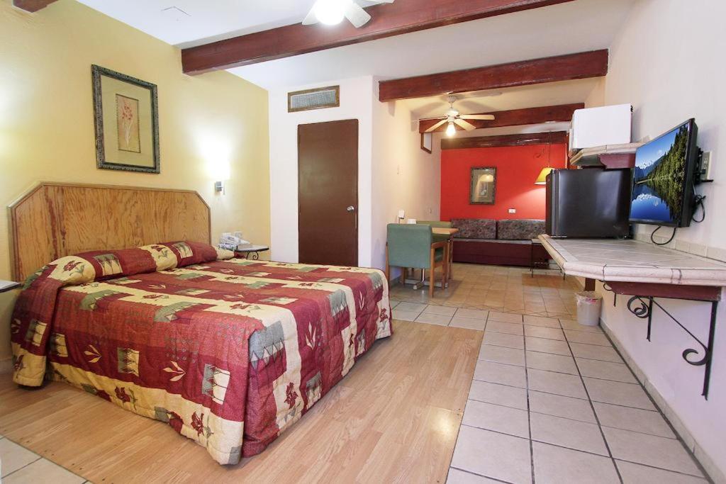 - une chambre avec un lit, une télévision et un bureau dans l'établissement Hotel Suites Kino, à Hermosillo