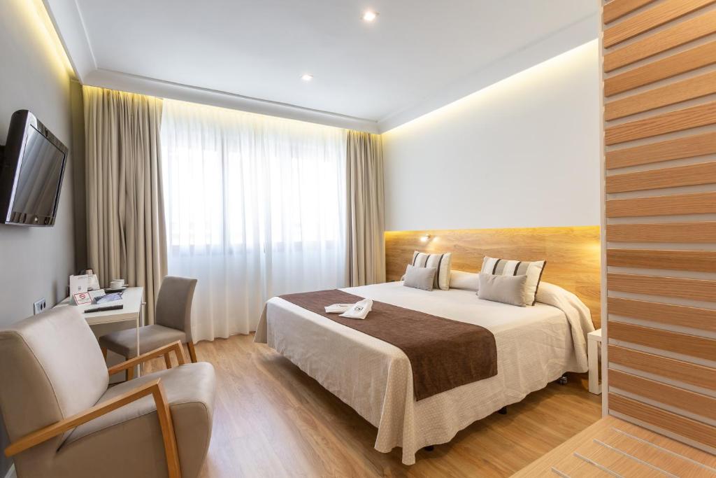 een hotelkamer met een bed en een stoel bij Monte Carmelo in Sevilla