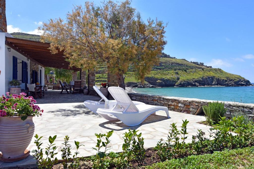 Dos sillas blancas sentadas en un patio junto al agua en The Stone Beach House in the area of Kampi, Koundouros en Ioulida