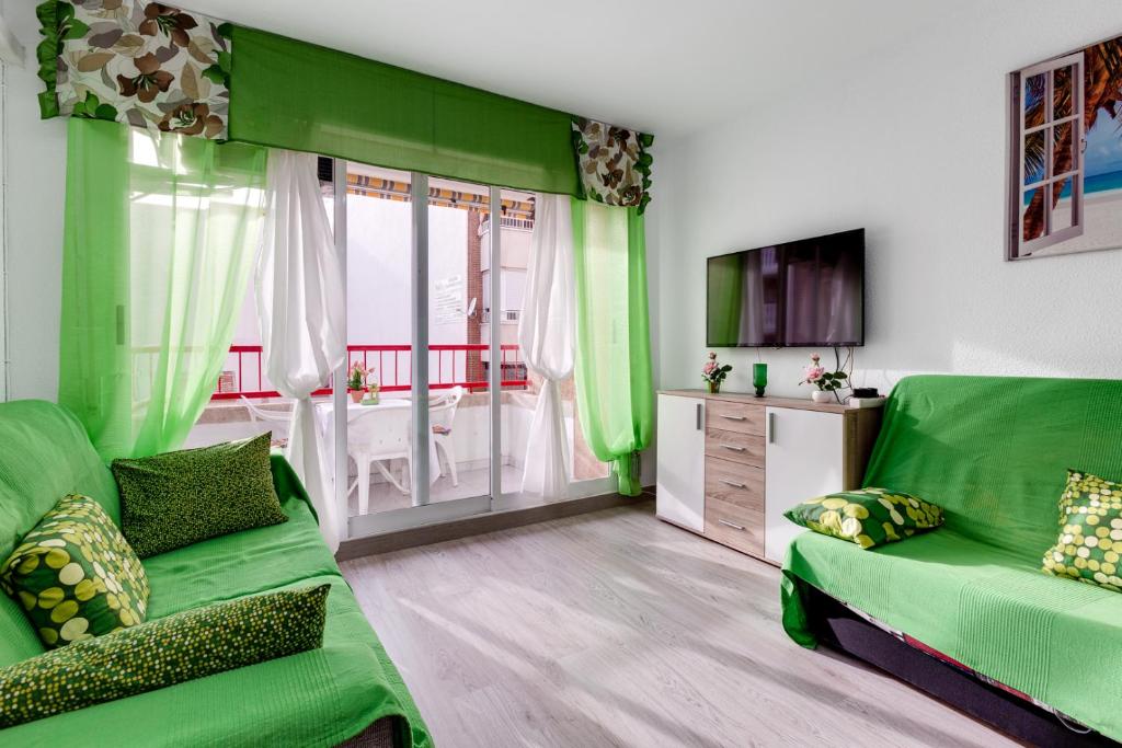 - un salon vert avec un canapé et une télévision dans l'établissement Apartment Studio Playa del Cura, à Torrevieja