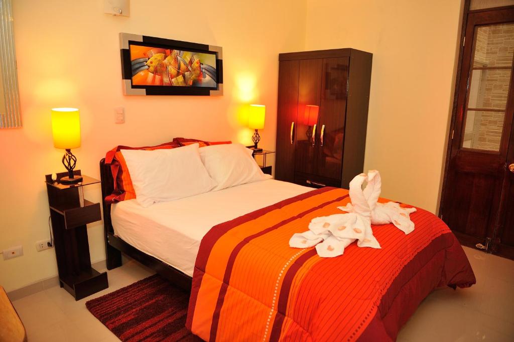 1 dormitorio con 1 cama con manta naranja y blanca en Tambo del Solar, en Arequipa