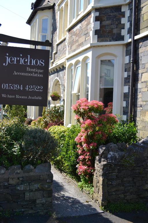 a sign in front of a house with flowers at Jerichos Boutique Accommodation in Windermere