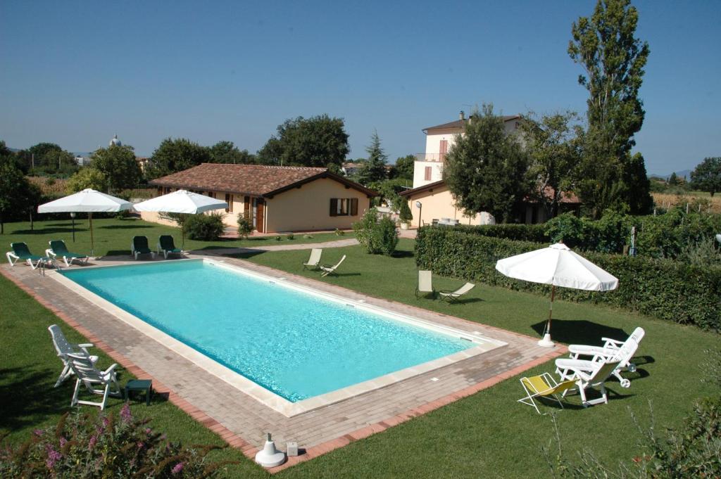 a swimming pool in a yard with chairs and umbrellas at Il Podere del Falco in Assisi
