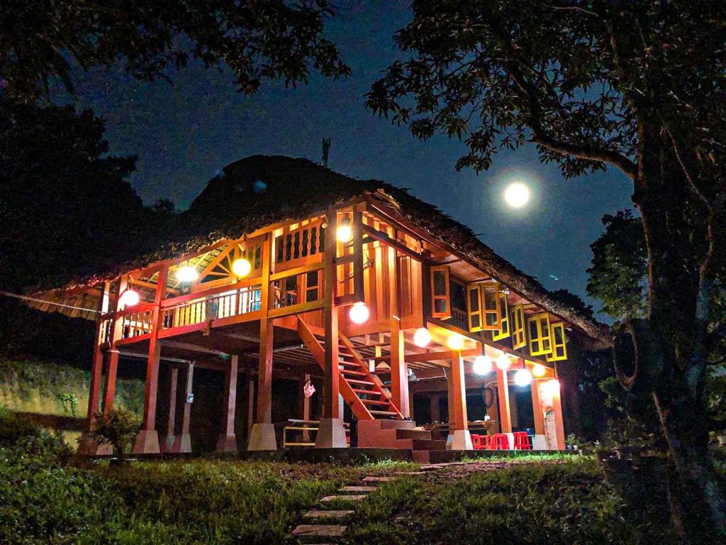 Pài Bjooc homestay في Làng Mán: منزل يضيء ليلا مع القمر