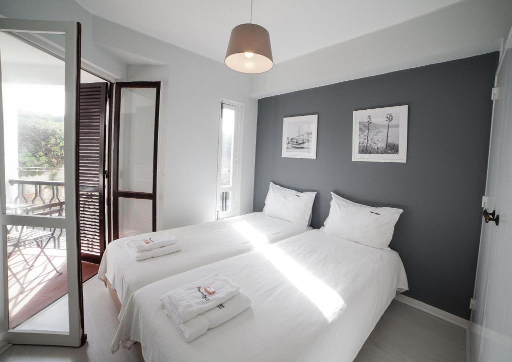 1 dormitorio con 1 cama blanca grande y 2 toallas en FLH - Ericeira Beach Apartments, en Ericeira