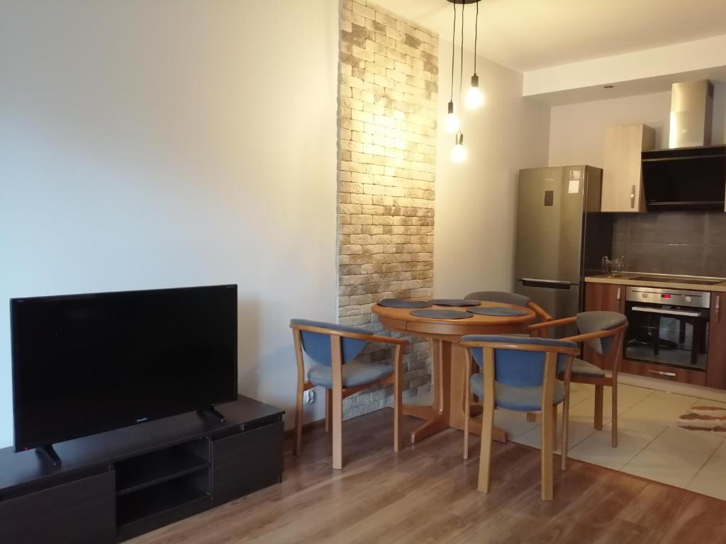 a kitchen with a table and chairs and a television at Apartament Pohulanka in Gdańsk