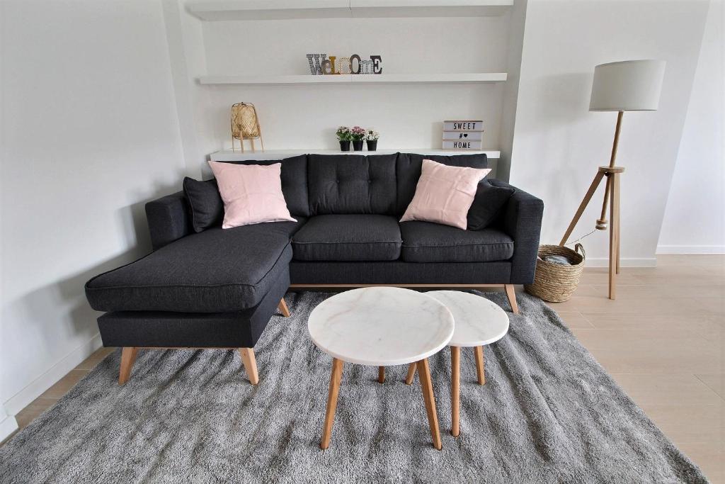 uma sala de estar com um sofá preto e uma mesa em Rent a flat - Montgomery em Bruxelas