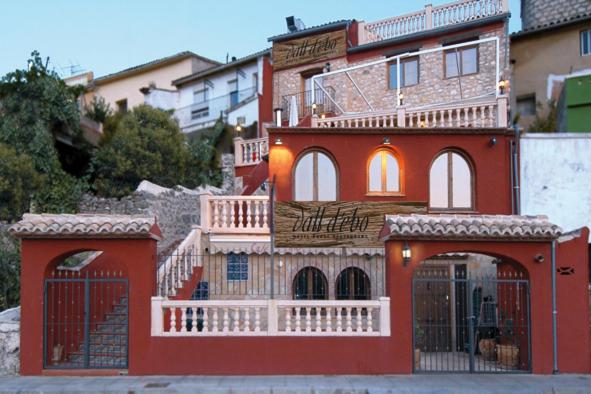 un edificio rojo con un balcón en el lateral. en Hotel Rural Barranc De L'ínfern, en Vall d'Ebo (Vall de Ebo)