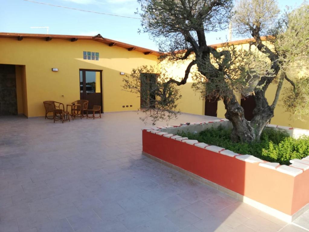 einen Innenhof mit einem Baum und einem gelben Gebäude in der Unterkunft Casa Acito in Stornara