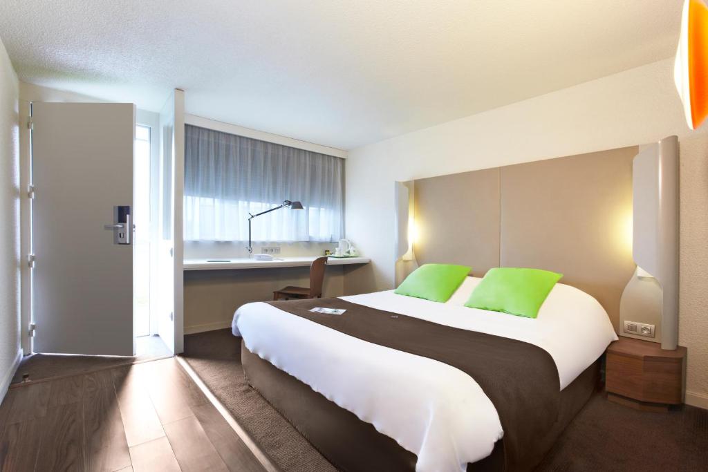 a hotel room with a large bed with green pillows at Campanile Rouen Est - Franqueville Saint Pierre in Franqueville-Saint-Pierre