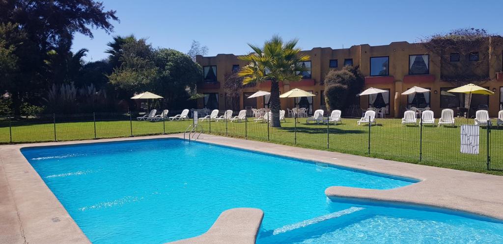 una piscina con sedie e un edificio sullo sfondo di Stellamar Apart Hotel a La Serena
