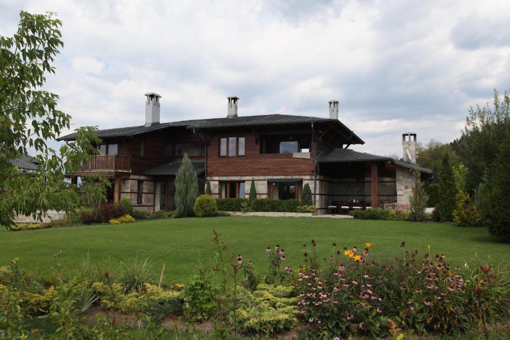 ein großes Holzhaus mit einem grünen Hof in der Unterkunft Ski & Spa Chalet Bansko in Bansko