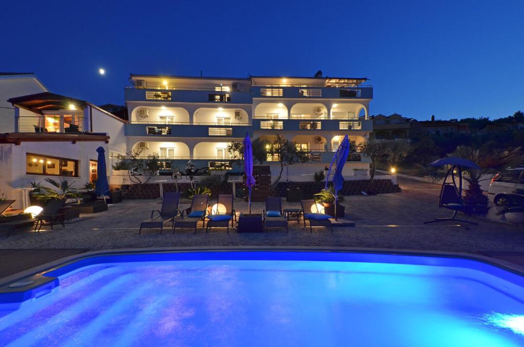 a swimming pool in front of a building at night at Apartments Silva in Trogir