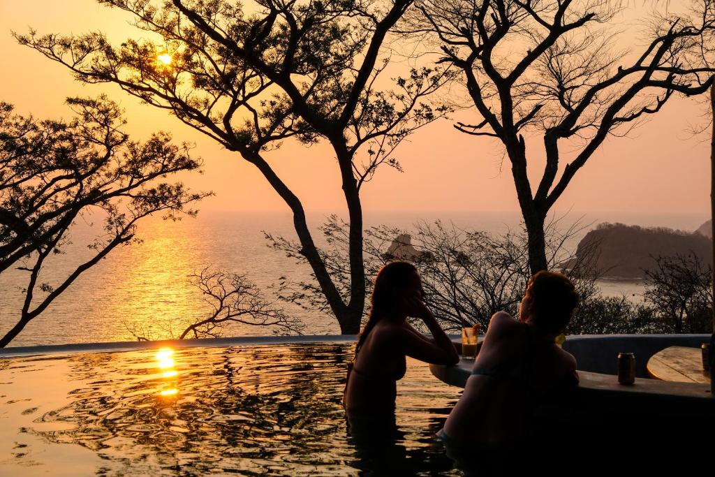 two women sitting in the infinity pool at sunset at Hush Maderas in San Juan del Sur