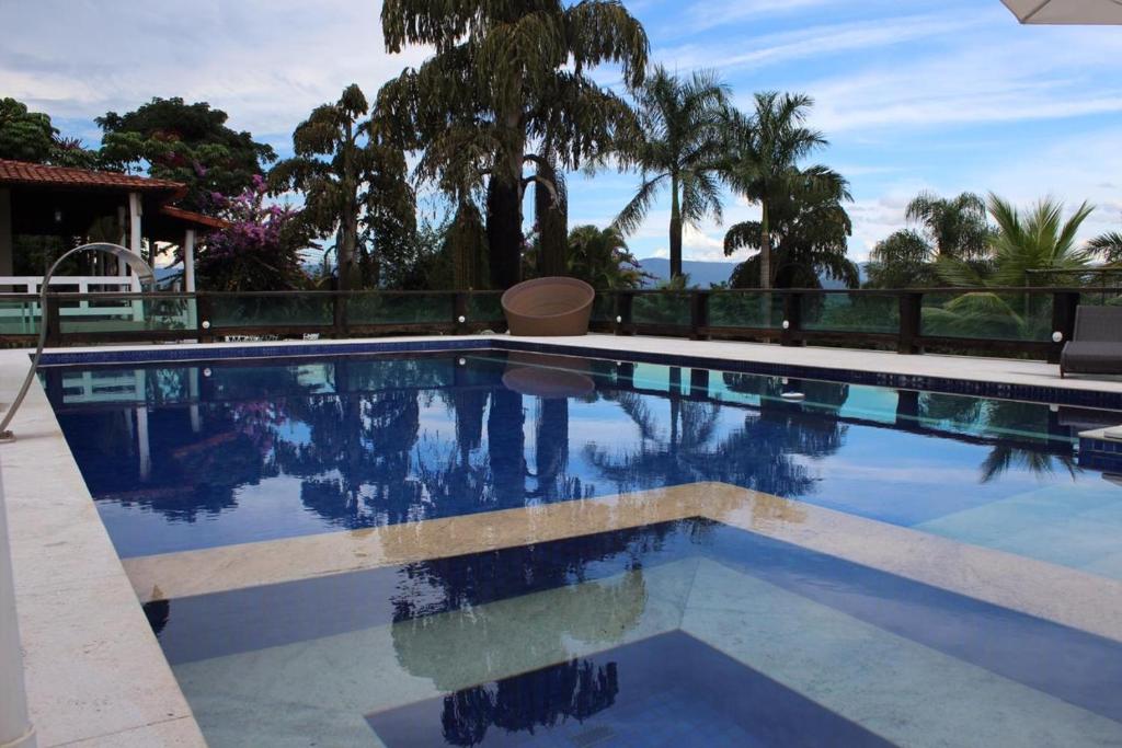 uma piscina com água azul e palmeiras em Fazenda Pedra Lisa Hotel Boutique em Brumadinho