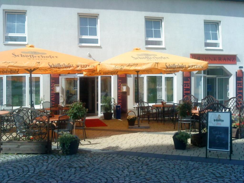 um pátio com mesas e guarda-sóis em frente a um edifício em Hotel und Restaurant Rosenkranz em Markranstädt